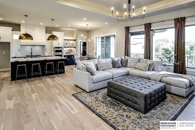 living room with light hardwood / wood-style floors, sink, and an inviting chandelier