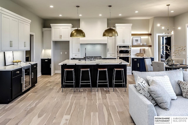 kitchen with white cabinetry, an island with sink, and hanging light fixtures