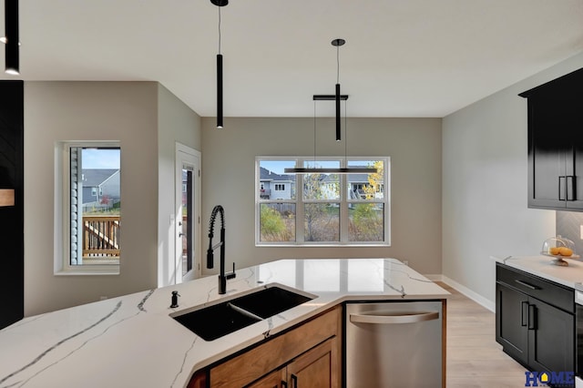 kitchen with dishwasher, sink, hanging light fixtures, light stone countertops, and plenty of natural light