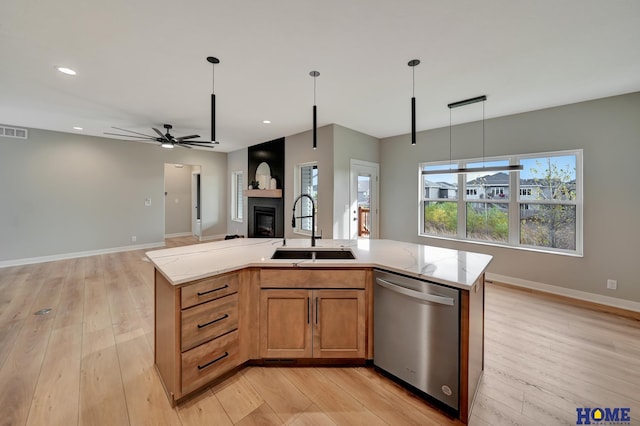 kitchen with sink, pendant lighting, light hardwood / wood-style flooring, dishwasher, and an island with sink