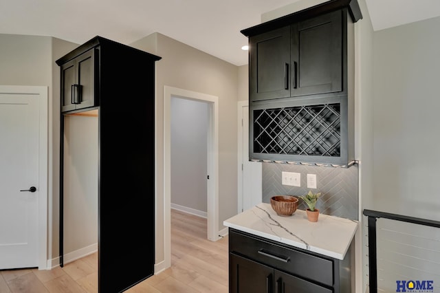 kitchen featuring light stone counters, light hardwood / wood-style flooring, and tasteful backsplash