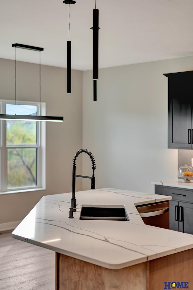 kitchen featuring sink, light hardwood / wood-style flooring, gray cabinets, light stone countertops, and decorative light fixtures