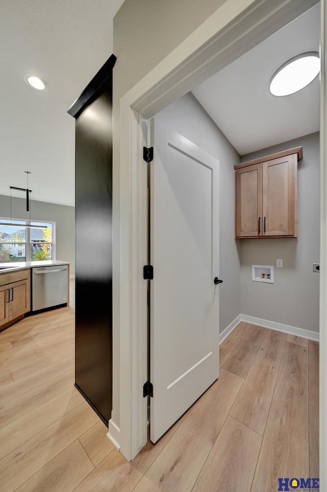 interior space with cabinets, hookup for a washing machine, and light hardwood / wood-style floors