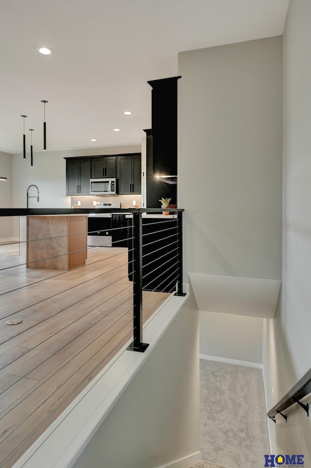 kitchen featuring hanging light fixtures, light carpet, and stainless steel appliances