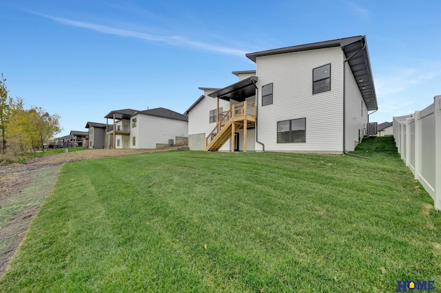 back of property featuring a deck and a lawn