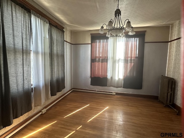 1424 4th Ave, Scottsbluff, NE 69361 - unfurnished dining area featuring a textured ceiling, radiator heating unit, dark wood-type flooring, and an inviting chandelier