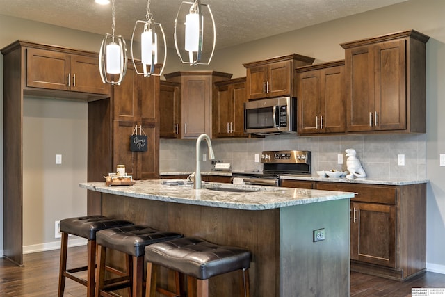 kitchen featuring dark hardwood / wood-style flooring, light stone countertops, and appliances with stainless steel finishes