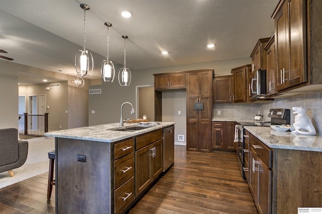 kitchen featuring an island with sink, sink, appliances with stainless steel finishes, and dark wood-type flooring