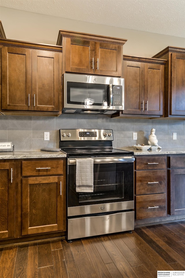 kitchen featuring tasteful backsplash, stainless steel appliances, and dark wood-type flooring