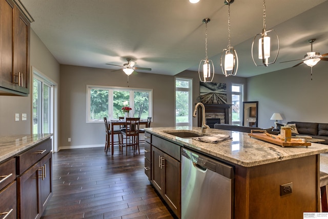 kitchen featuring stainless steel dishwasher, sink, decorative light fixtures, a center island with sink, and dark hardwood / wood-style floors