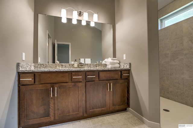 bathroom with tile patterned flooring, vanity, and a tile shower