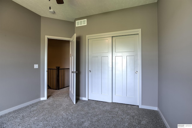 unfurnished bedroom featuring carpet flooring, ceiling fan, a closet, and a textured ceiling