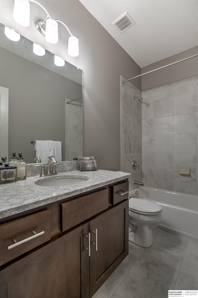 full bathroom with a textured ceiling, vanity, toilet, and tiled shower / bath