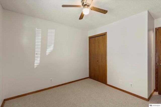 carpeted empty room featuring ceiling fan and a textured ceiling