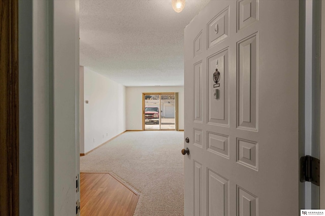 hallway with carpet flooring and a textured ceiling