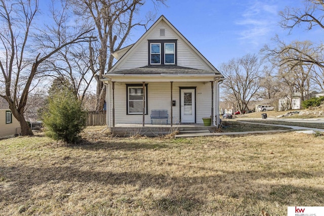 bungalow featuring covered porch and a front yard