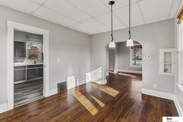 unfurnished dining area with dark hardwood / wood-style flooring, a drop ceiling, and sink