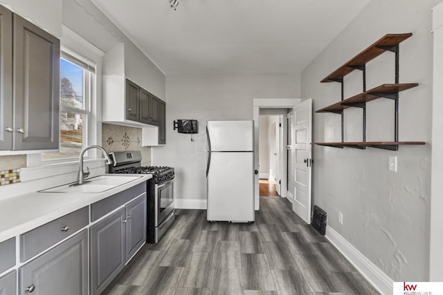 kitchen featuring gray cabinets, dark hardwood / wood-style floors, white refrigerator, and gas range