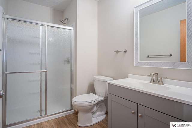 bathroom featuring vanity, toilet, wood-type flooring, and a shower with shower door