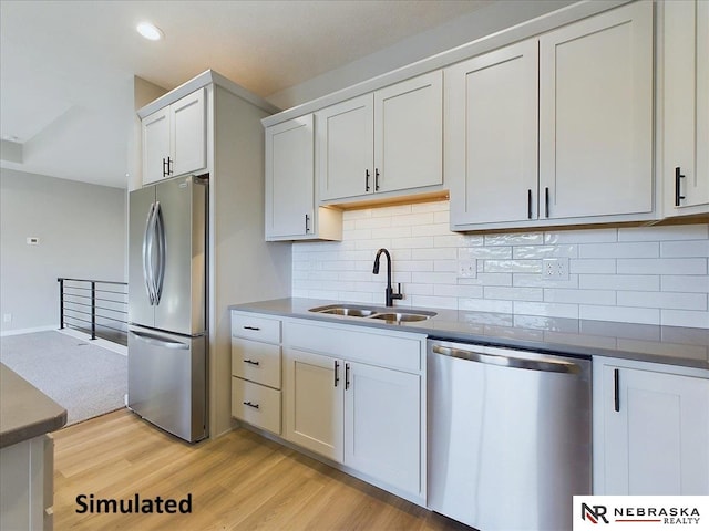 kitchen featuring white cabinets, sink, light hardwood / wood-style flooring, decorative backsplash, and stainless steel appliances