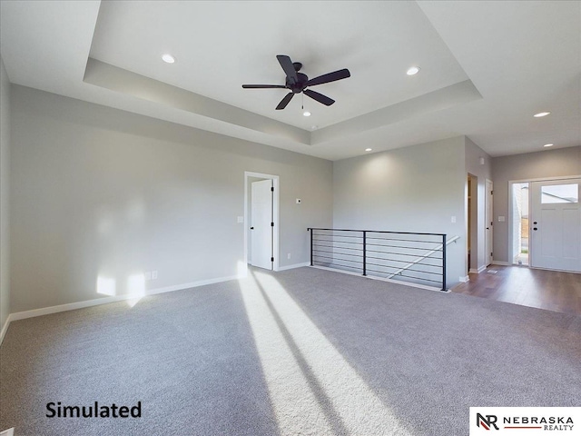 unfurnished room featuring a tray ceiling, hardwood / wood-style flooring, and ceiling fan