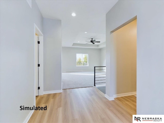 hall with a raised ceiling and light hardwood / wood-style floors