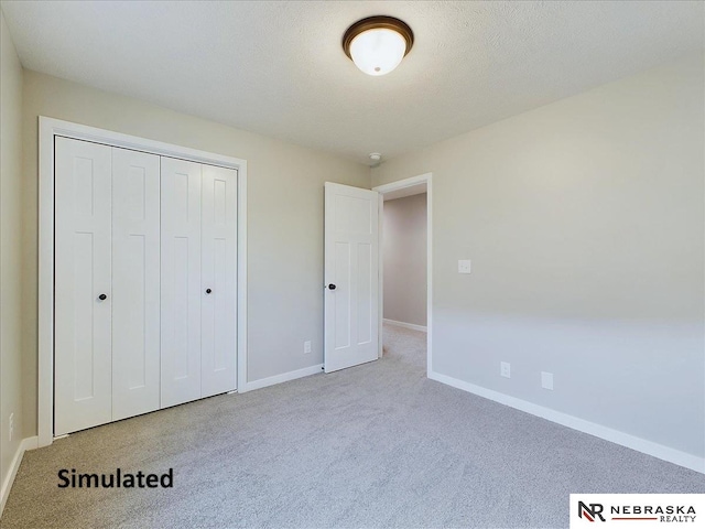 unfurnished bedroom featuring light colored carpet, a textured ceiling, and a closet