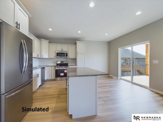 kitchen featuring decorative backsplash, appliances with stainless steel finishes, a kitchen island, light hardwood / wood-style flooring, and white cabinetry