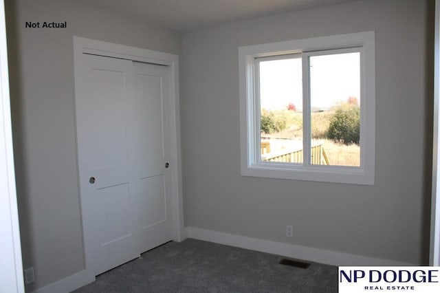 unfurnished bedroom featuring dark carpet and a closet