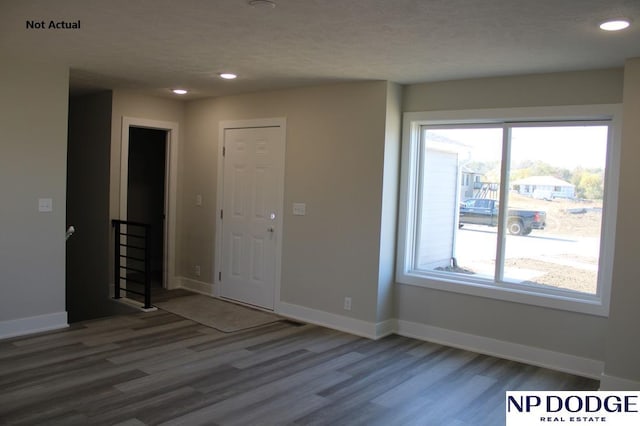 empty room featuring a textured ceiling, hardwood / wood-style flooring, and plenty of natural light