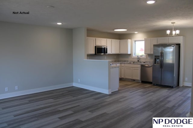 kitchen featuring dark wood-type flooring, an inviting chandelier, sink, appliances with stainless steel finishes, and white cabinetry