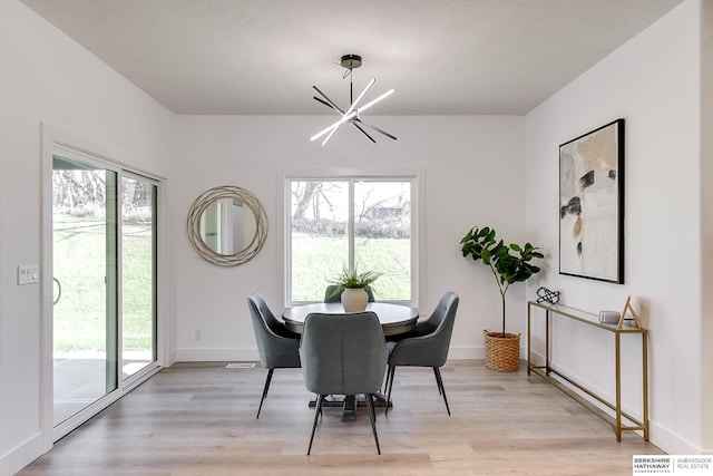 dining area featuring light wood-type flooring and an inviting chandelier