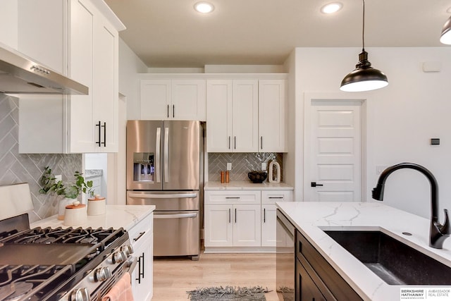 kitchen featuring light stone countertops, white cabinetry, stainless steel appliances, and extractor fan