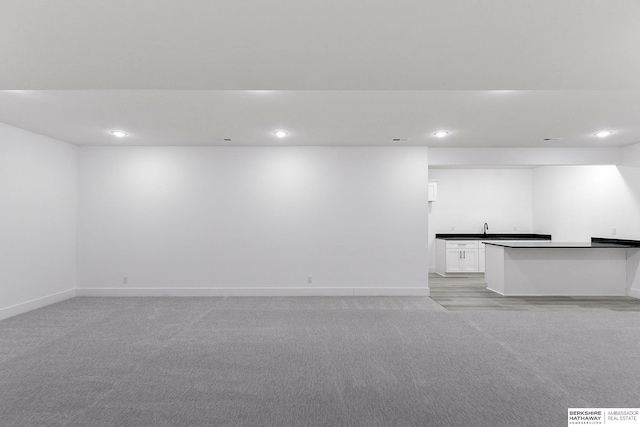 unfurnished living room featuring light carpet and sink