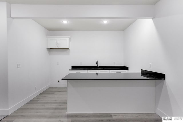 kitchen featuring kitchen peninsula, sink, white cabinets, and light wood-type flooring