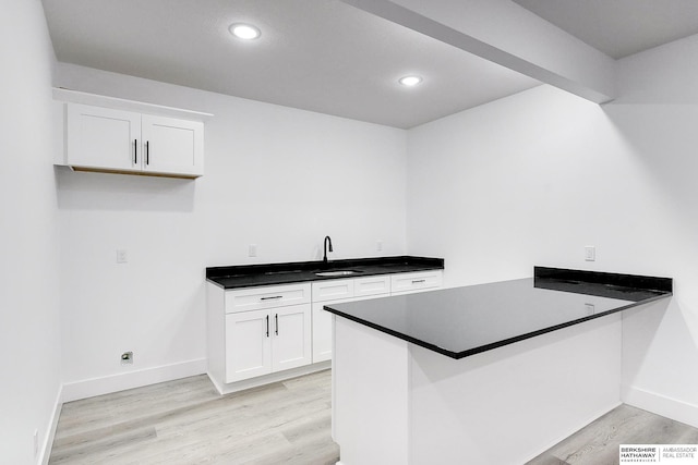 kitchen with light wood-type flooring, white cabinetry, and kitchen peninsula