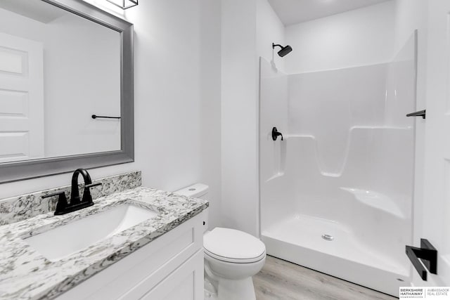 bathroom featuring a shower, wood-type flooring, vanity, and toilet