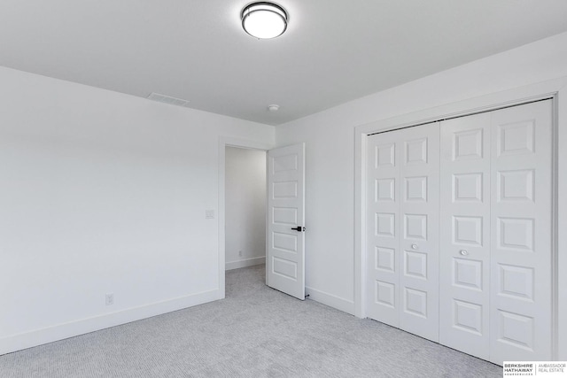 unfurnished bedroom featuring light colored carpet and a closet