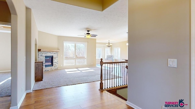 corridor featuring hardwood / wood-style floors, a textured ceiling, and a notable chandelier