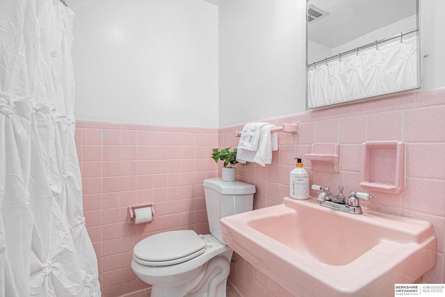 bathroom with sink, tile walls, and toilet