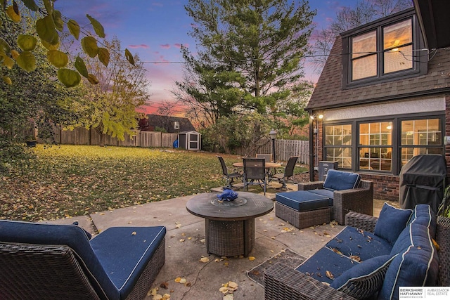 patio terrace at dusk with a lawn, a shed, and an outdoor hangout area