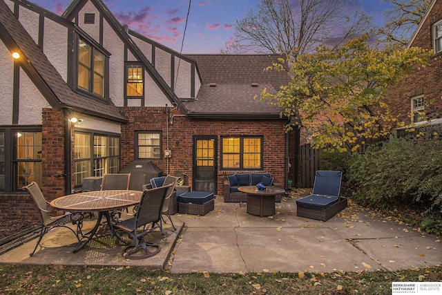 back house at dusk with outdoor lounge area and a patio