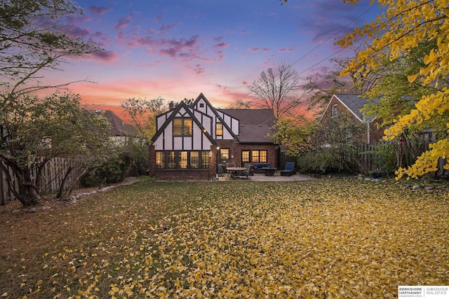 back house at dusk with a patio area and a yard