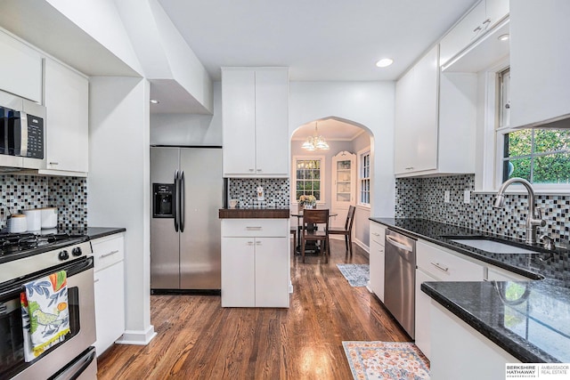 kitchen with white cabinets, sink, dark stone countertops, dark hardwood / wood-style flooring, and stainless steel appliances