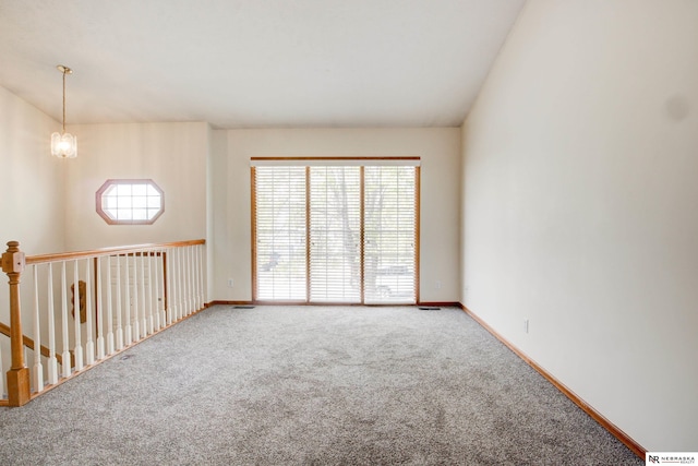 empty room with carpet, a notable chandelier, lofted ceiling, and a wealth of natural light