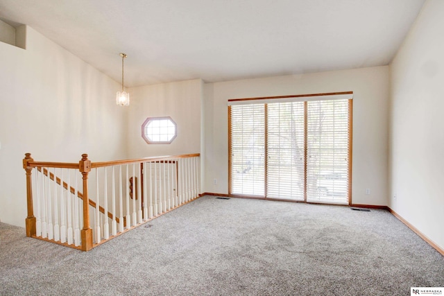 carpeted spare room with a notable chandelier