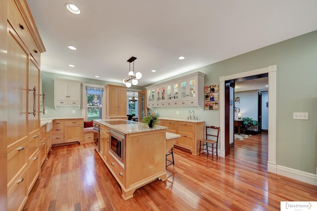 kitchen with a kitchen bar, a center island, stainless steel microwave, and light wood-type flooring