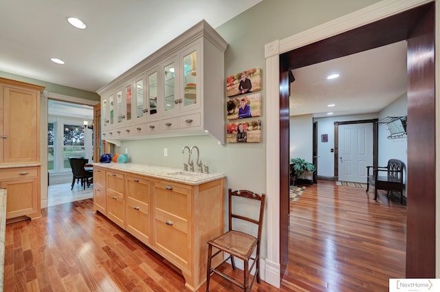 interior space featuring light hardwood / wood-style floors, light stone countertops, sink, and light brown cabinets