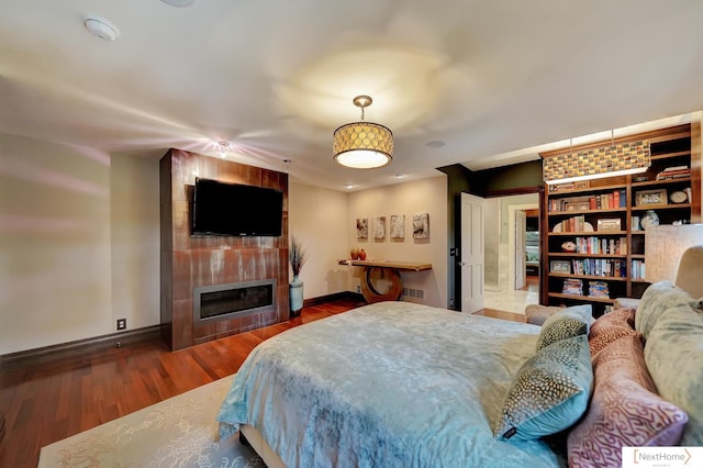 bedroom with a fireplace and dark wood-type flooring