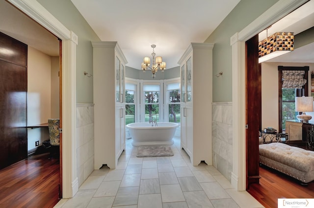 bathroom featuring a tub, hardwood / wood-style floors, a chandelier, and tile walls